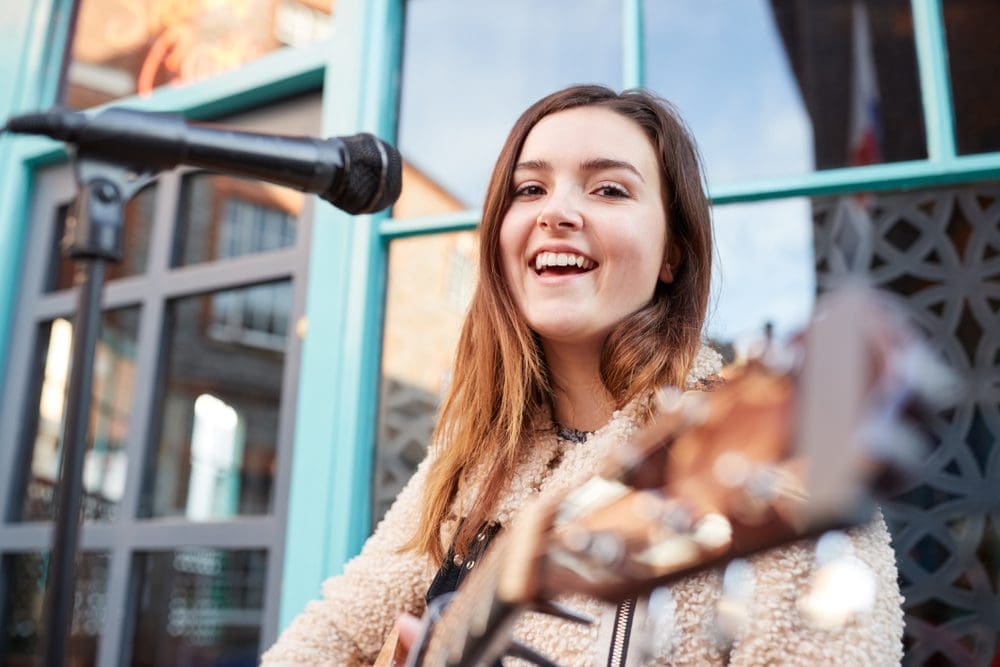 Portrait,Of,Young,Female,Musician,Busking,Playing,Acoustic,Guitar,And