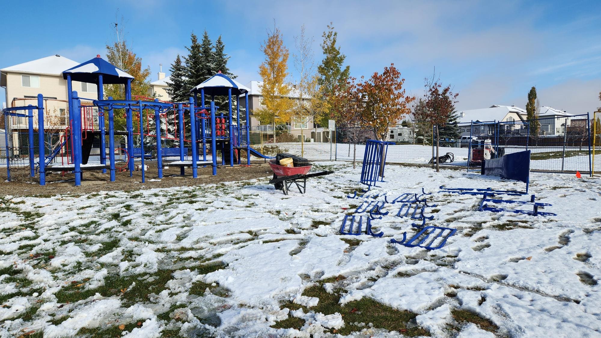 A photograph of the Hawkmere Playground. Equipment has been removed and a wheelbarrow can be seen beside the playground