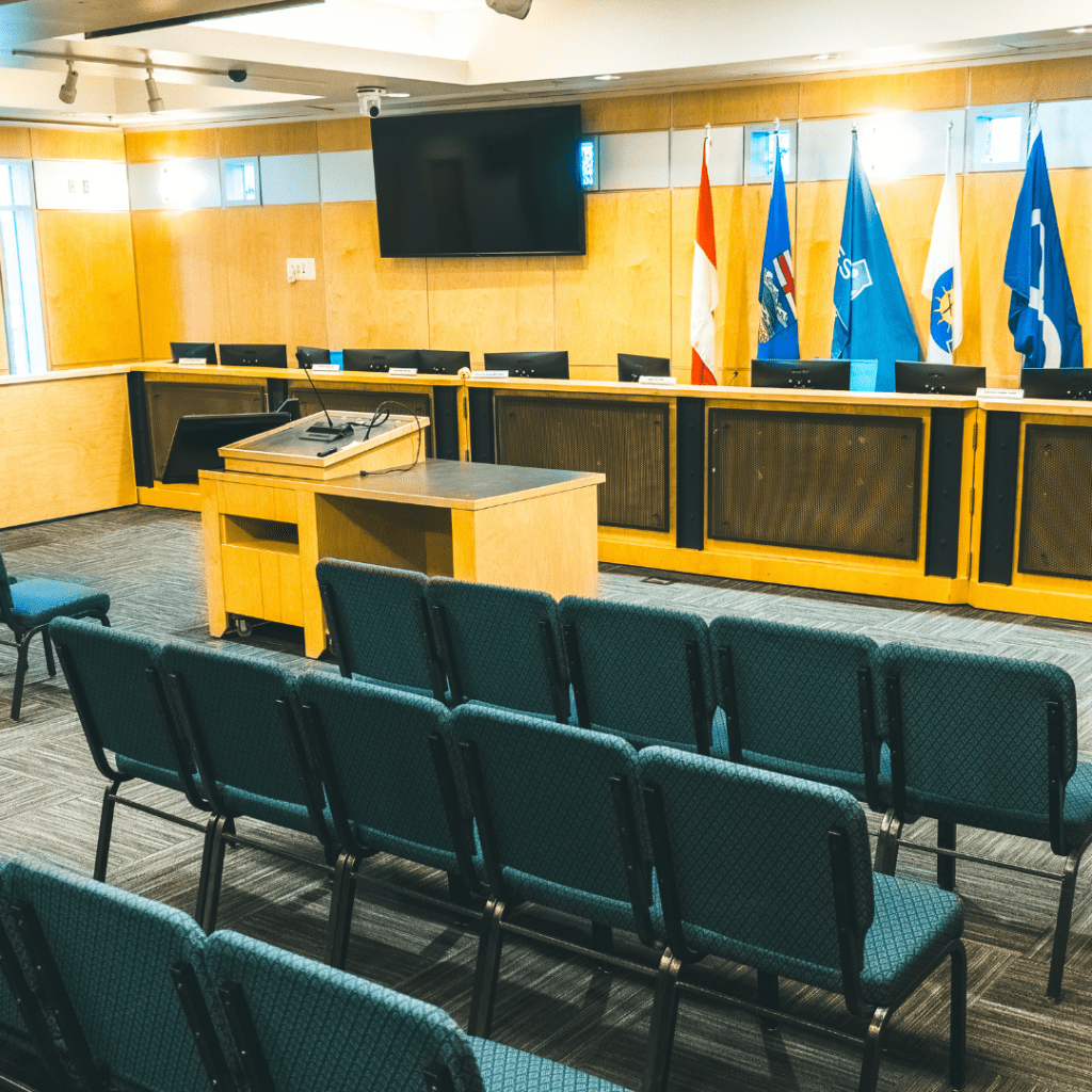 A photo of City Council Chambers picturing empty chairs & flags
