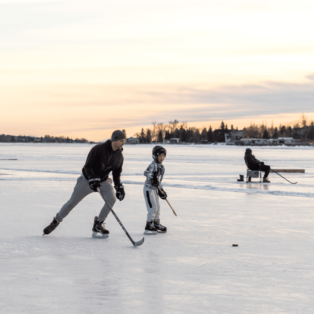 A father and son play ice hockey on Chestermere Lake.
